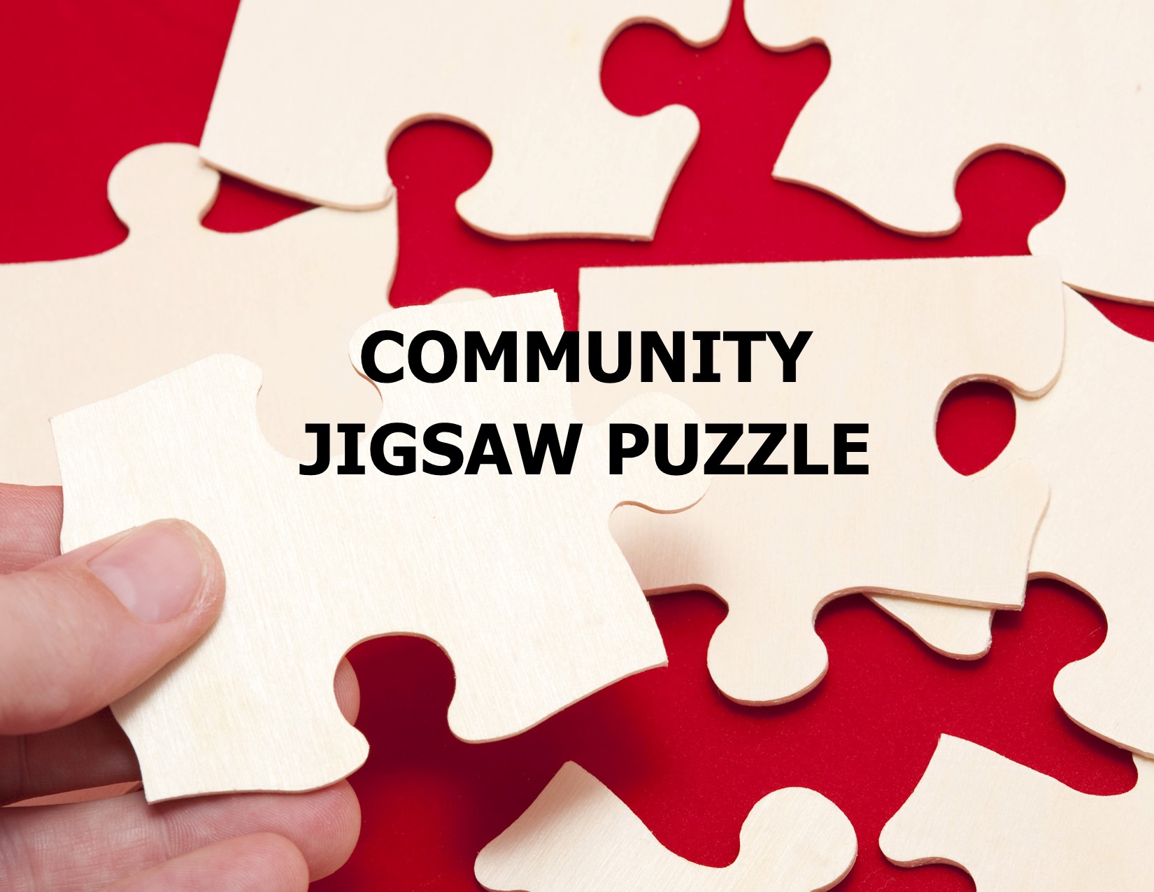 Community Jigsaw Puzzle Image of a hand holding a jigsaw puzzle piece to be fitter into a puzzle in the background. Puzzle pieces are plain white and the background is red.