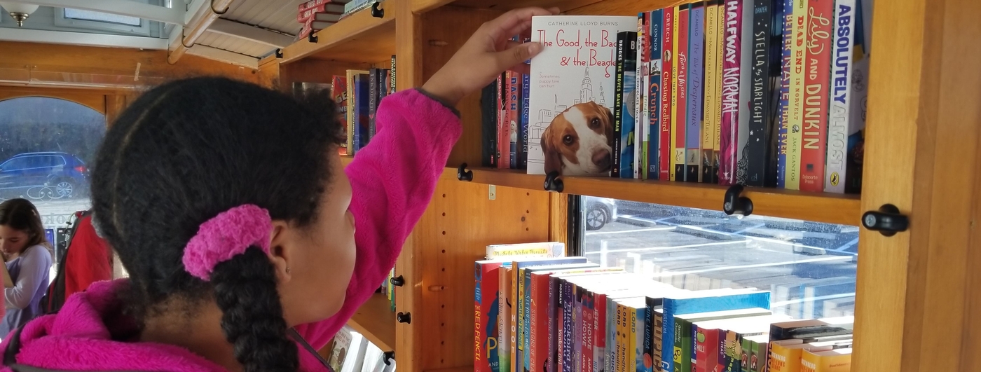 Girl broses through books on shelf Girl browsing shelf