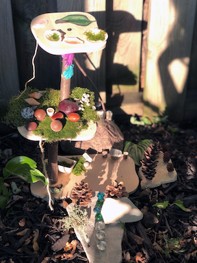 Fairy house with moss, leaves, rocks, branches, pinecones, and other natural items.