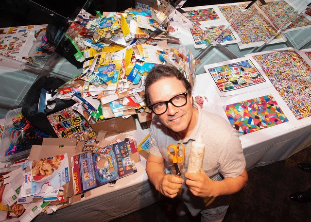 Artist Michael Albert with collage materials, smiling at the camera, and holding up a pair of scissors