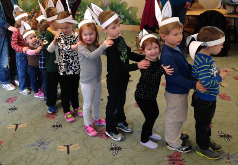 Line of kids doing the bunny hop wearing bunny ears.