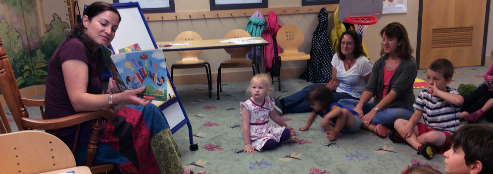 Teacher Krista Thusius reads "Siesta" to a group of children, parents and grandparents