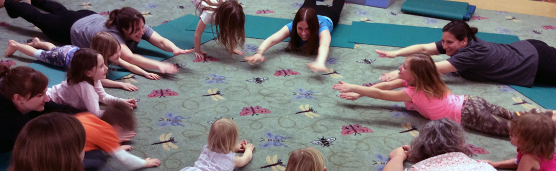 Circle of kids and moms stretching on the storytime room carpet.