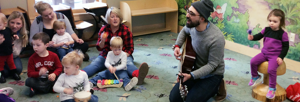 Corey Hart plays the guitar with children and their caregivers.