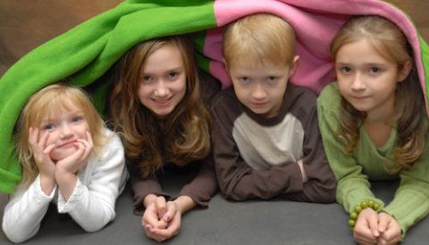 4 kids all together under a blanket