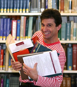 Chris Fascione holding books and scripts, smiling
