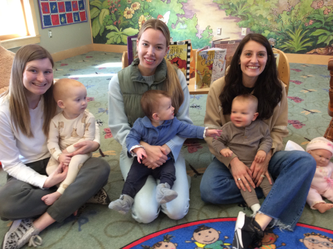 3 moms with babies in their laps, smiles on their faces