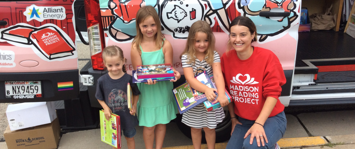 Madison Reading Project staff and children stand in front of Big Red Bus.